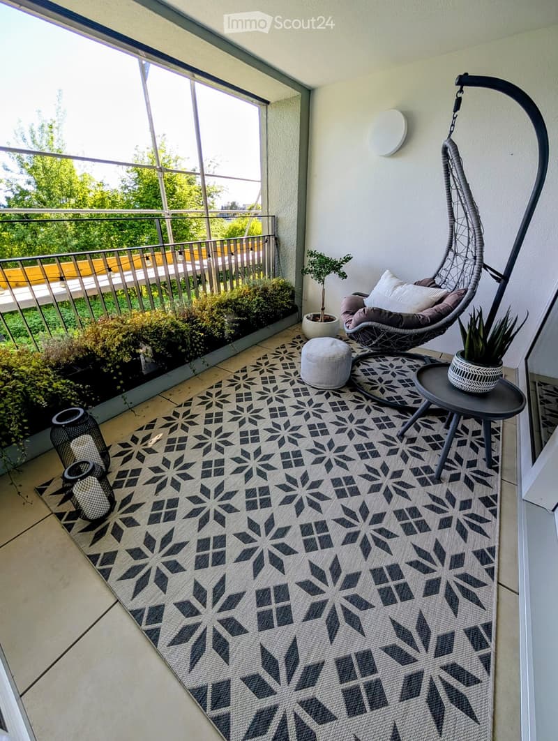 Balcony with hanging chair, rug, table, plants, and lanterns