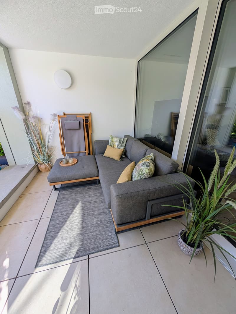 Balcony with a sectional sofa, rug, plants, and a table with candles