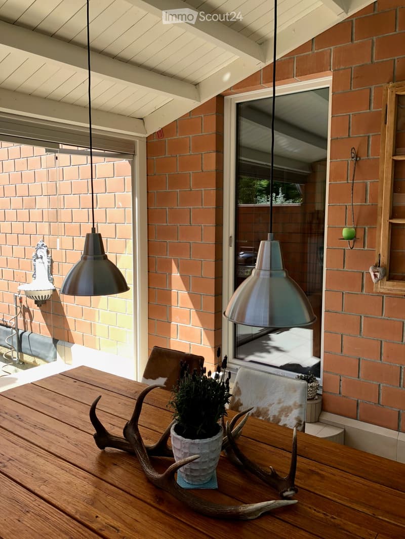 wooden table, hanging lamps, brick wall, glass door, plant, deer antlers