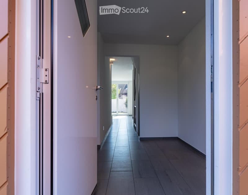 Empty hallway with white walls, wooden floor, and ceiling lights