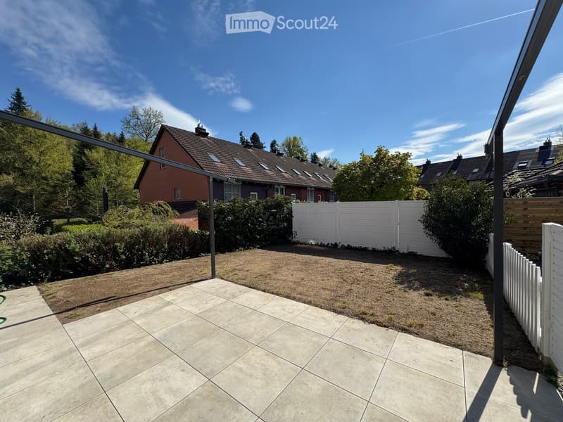 tiled patio, white fence, metal pergola, brown grass, trees, houses in the background