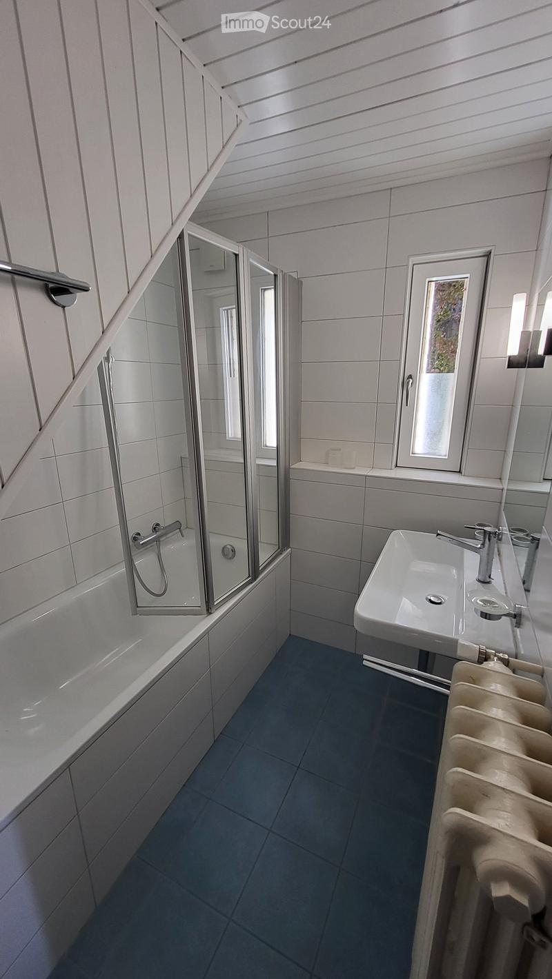 Bathroom with white tiles, blue floor, bathtub, shower, sink, radiator, window