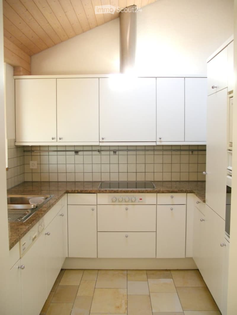 Modern kitchen with white cabinets, granite countertops, stainless steel sink, and built-in oven.