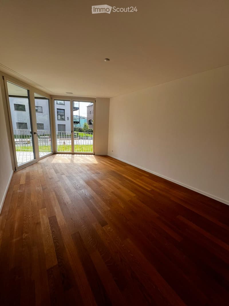 Empty room with hardwood floors, white walls, and large glass doors leading to a balcony.