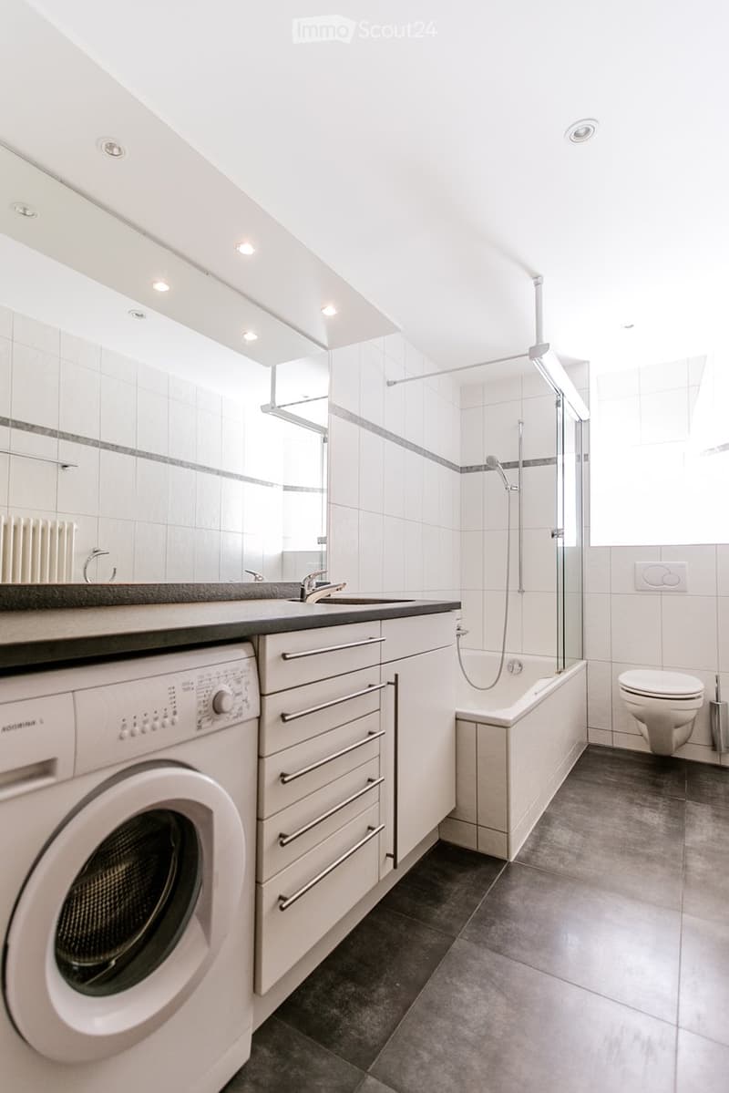 modern bathroom with white tiles, bathtub, shower, toilet, washing machine, sink, cabinets, mirror