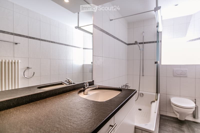 modern bathroom with white tiles, double sink, mirror, bathtub, shower, toilet