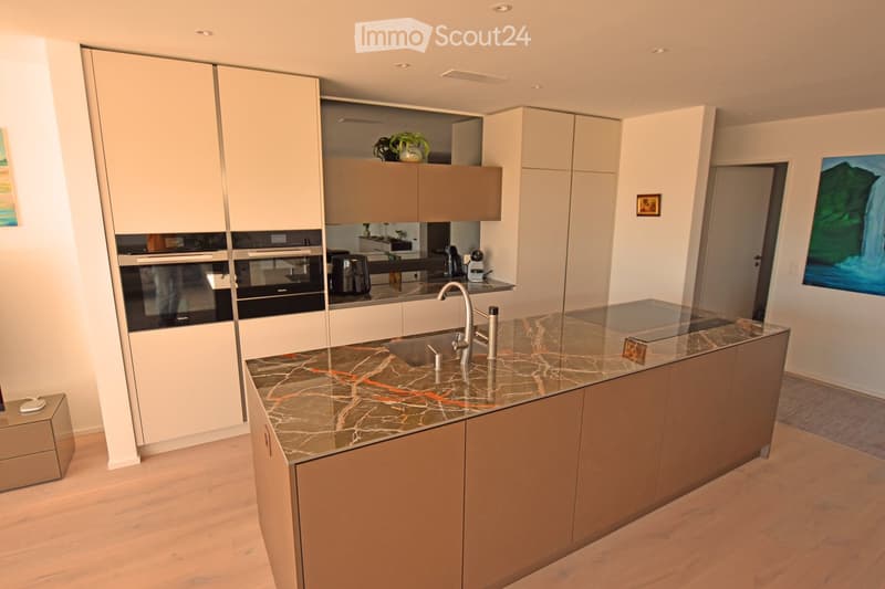 modern kitchen with marble countertop, stainless steel appliances, wooden floor, white cabinets, artwork on the wall