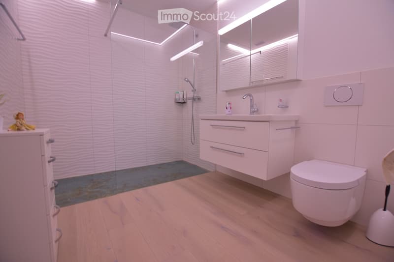 modern bathroom with white tiles, wooden floor, shower, sink, toilet, mirror, and cabinet