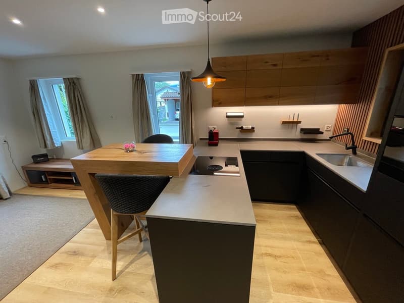 wooden island countertop, modern wooden cabinets, countertop sink, central gas stove, windows, pendant light, dark hardwood floors, neutral color scheme
