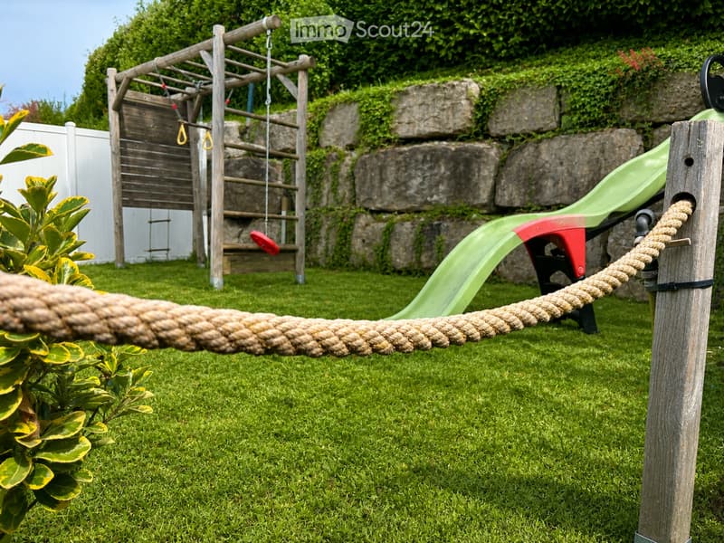 Garden / Outdoor Area. Outdoor play area with a rope, slide, swing, ladder, and plant.