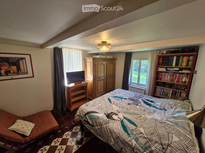 Bedroom. Cozy bedroom with a double bed, a small sofa, a television on a wooden stand, a wooden cabinet, a bookshelf filled with books, and a picture frame on the wall.