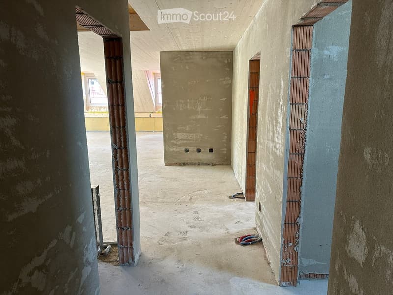 Unfurnished Room. Empty hallway with unfinished concrete walls and floor, exposed pipes, and construction materials visible.