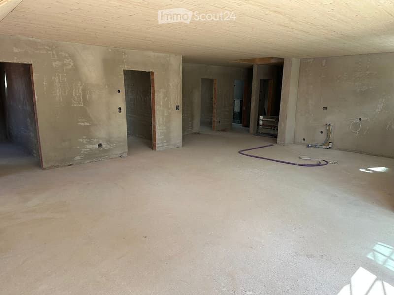 Unfurnished Room. Empty room with unfinished concrete floor and walls, exposed wooden ceiling, and several doorways leading to other spaces.