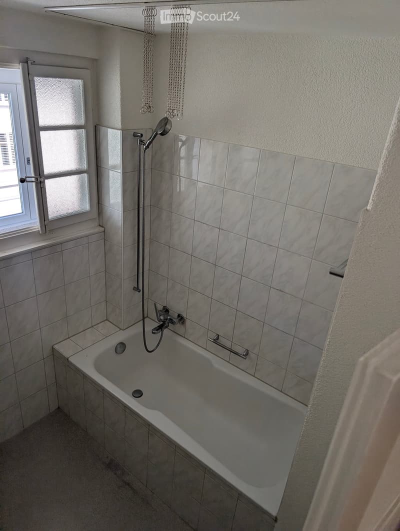 Bathroom with bathtub, shower head, and tiled walls