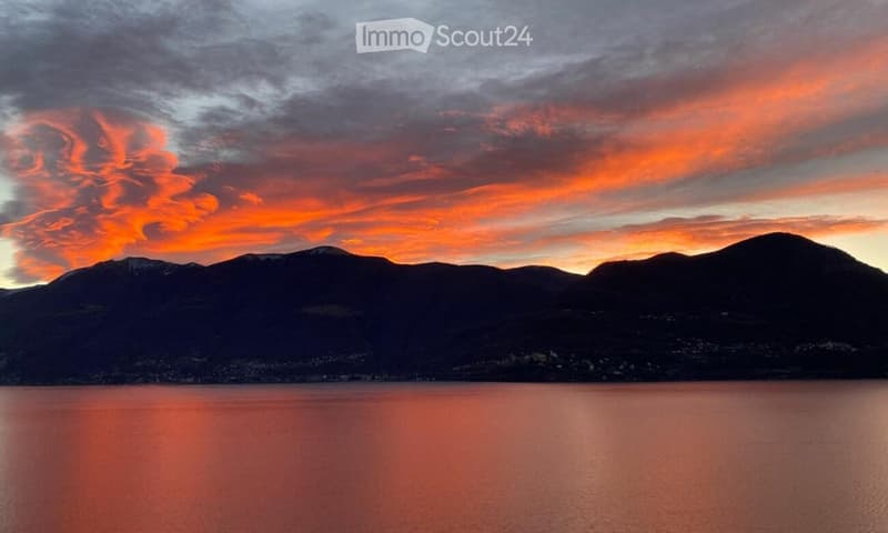 A landscape with mountains and a lake under a colorful sunset