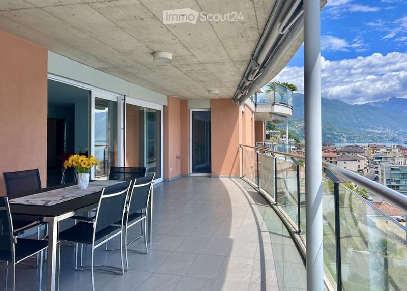 Balcony with dining table, vase of flowers, glass railings, tile floor