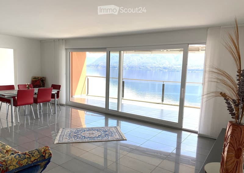 dining room with table and chairs, large sliding glass doors, balcony with ocean view, rug, couch, vase