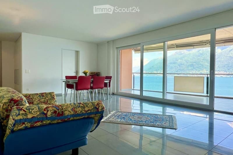 spacious living room with blue couch, dining table, and sea view balcony