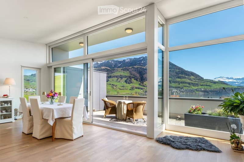 Furnished Room. Bright dining area with large windows offering scenic mountain views, featuring a dining table with chairs, a flower vase, and a sideboard with table lamps.