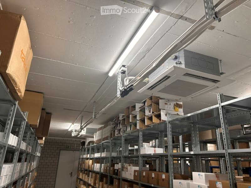 Other. Warehouse space with metal shelving units filled with cardboard boxes, fluorescent lighting, and an air conditioning unit mounted on the ceiling.