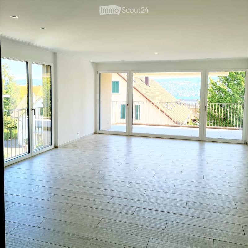 Unfurnished Room. Empty room with light wooden flooring, white walls, and large sliding glass doors leading to a balcony with a scenic view.