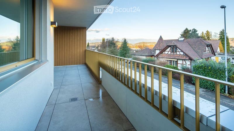 Balcony / Terrace. Modern balcony with tiled floor, wooden railing, large window, and scenic view of houses and trees.