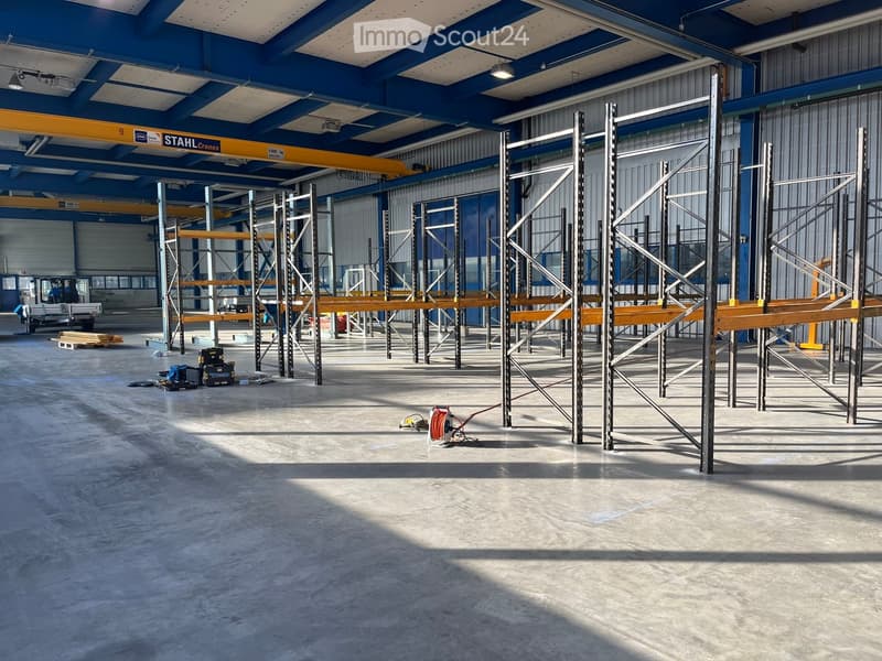 large warehouse with high ceiling, metal shelves and racks, open floor plan, grey concrete flooring