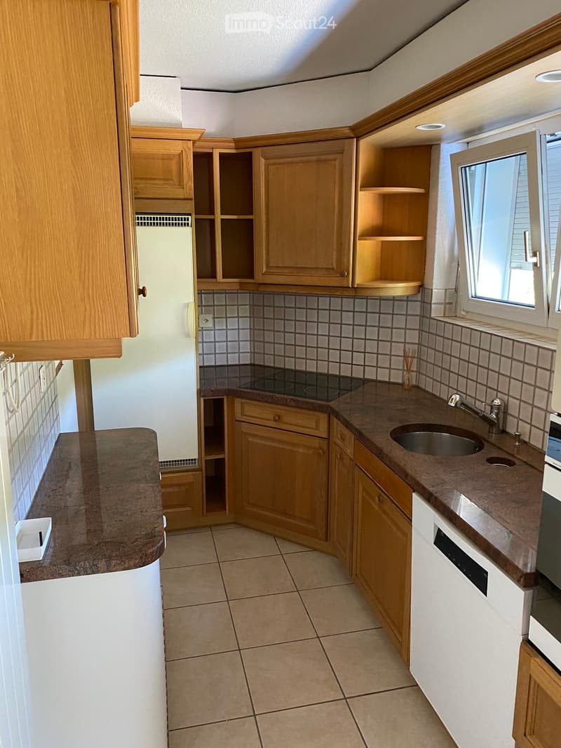 Compact kitchen with wooden cabinets, granite countertops, electric stove, sink, and refrigerator.