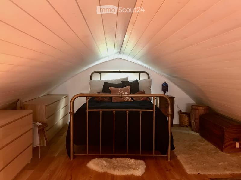 Bed with a canopy, wooden furniture, two rugs, a lamp, and baskets