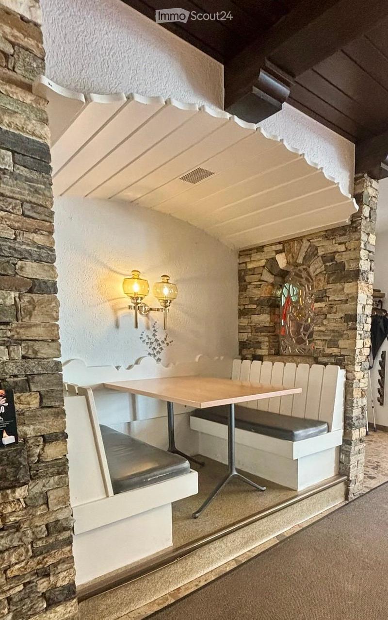 Cozy dining area with a wooden table, built-in bench seating, stone walls, and decorative wall-mounted lamps.