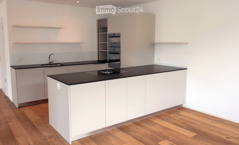 Modern kitchen with white cabinets, black countertops, a central island, and built-in appliances including an oven and sink.