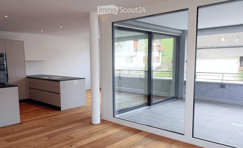Modern kitchen with light-colored cabinets, a central island, and large glass sliding doors leading to a balcony.