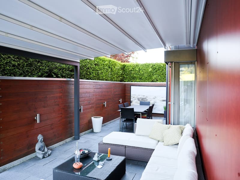 Modern outdoor terrace with a white sofa, glass coffee table, dining area, and decorative items.