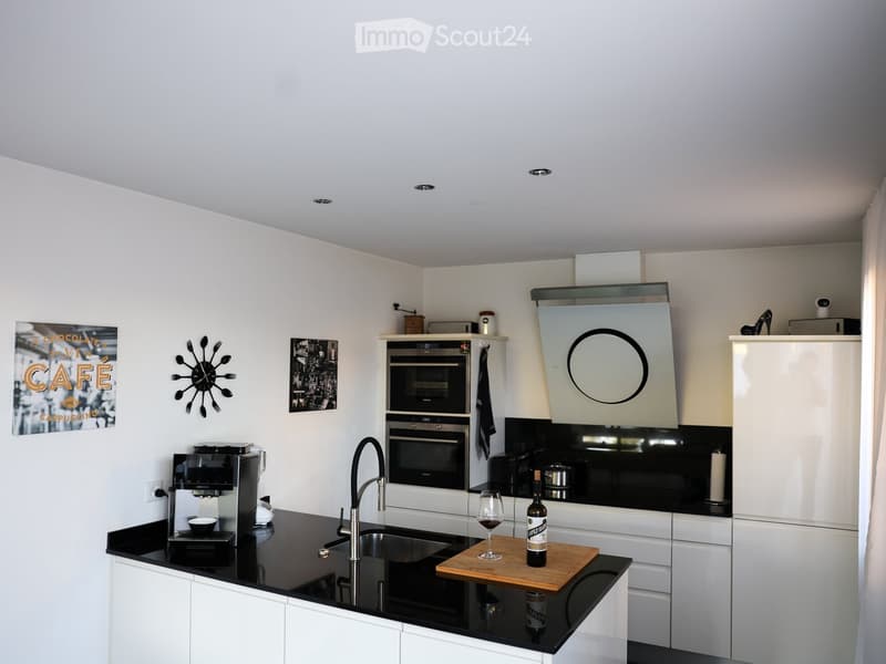 Modern kitchen with white cabinets, black countertops, stainless steel appliances, and a sleek design.