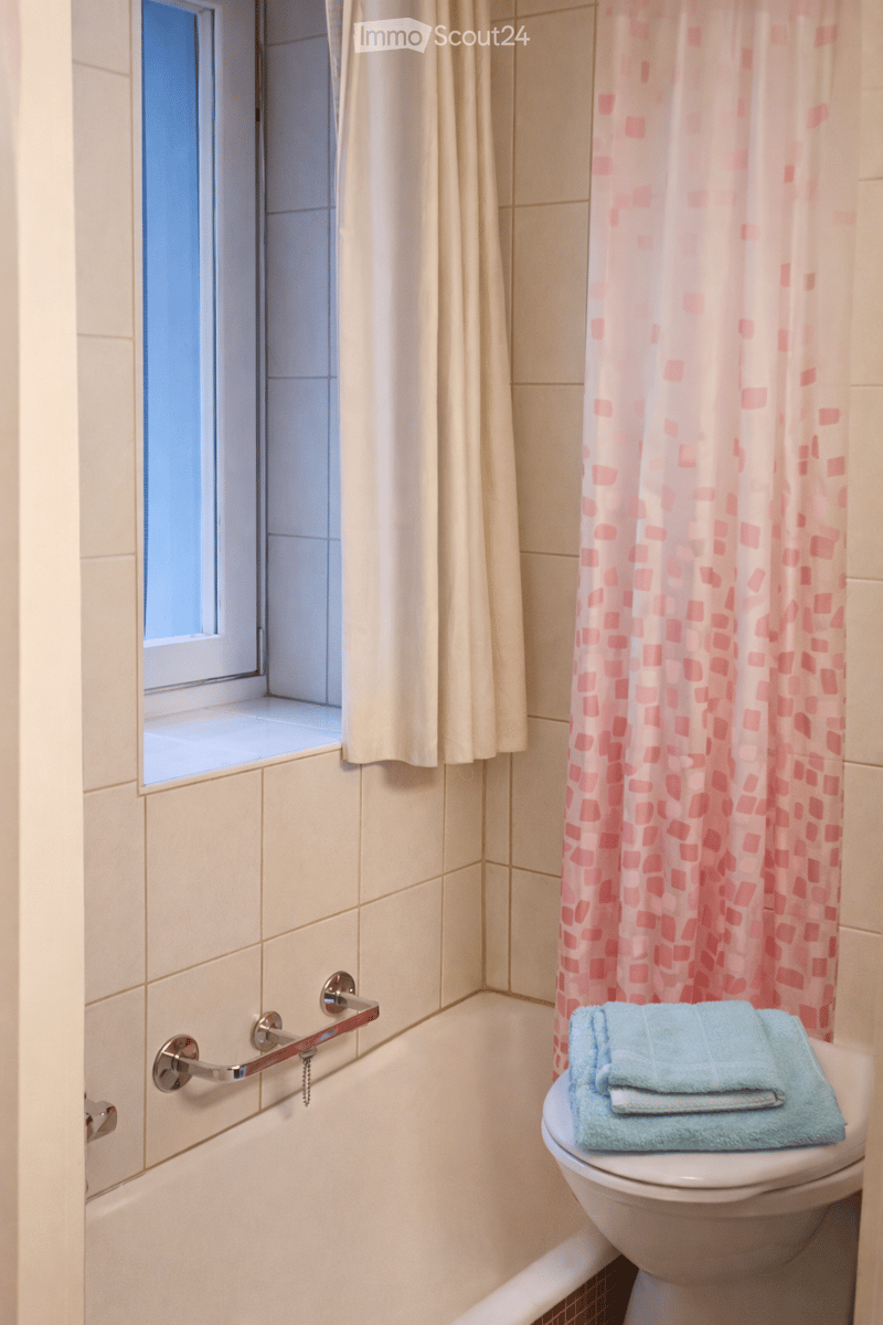 tiled walls and floor, bathtub, toilet, window with shower curtain