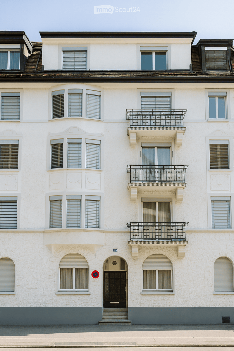 3 story building, white paint, black windows, balconies, gray ground floor
