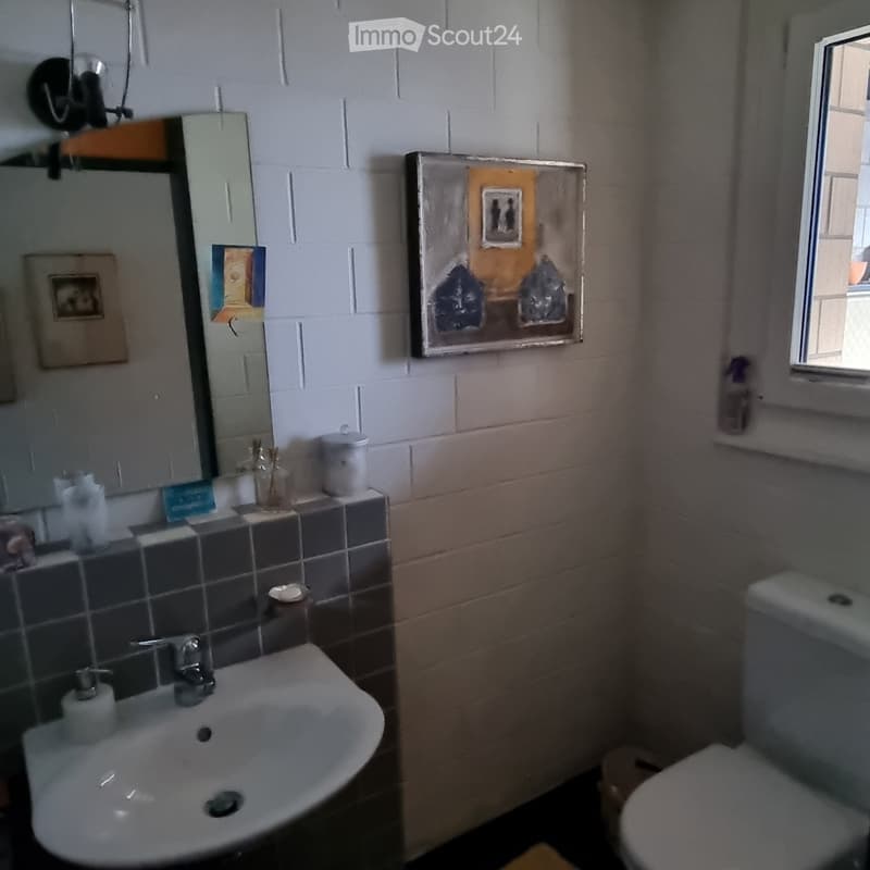 Bathroom with sink, mirror, toilet, and window