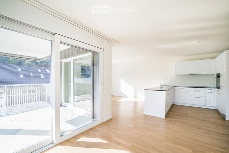 Modern, minimalist kitchen with white cabinets, a central island, and a large glass sliding door leading to a balcony.