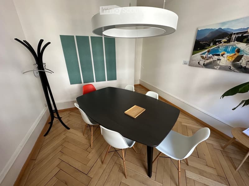 Dining room with a black dining table, white chairs, a coat rack, a pendant light, and a large painting of a pool area.