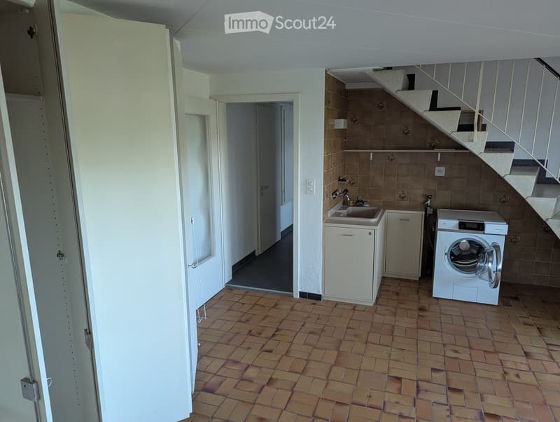 Laundry room with tiled floor, washing machine, sink, and cabinet.