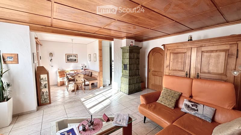 wooden ceiling, white tiles, wooden furniture, orange couch, glass table, potted plant, dining table, chairs, wooden cabinet, green cabinet, picture frames