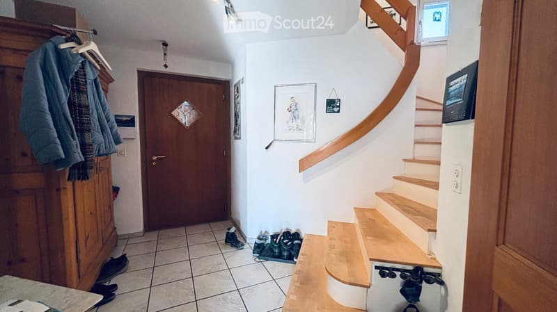 entryway with wooden door, wooden stairs, tiled floor, wooden coat rack, shoes on the floor