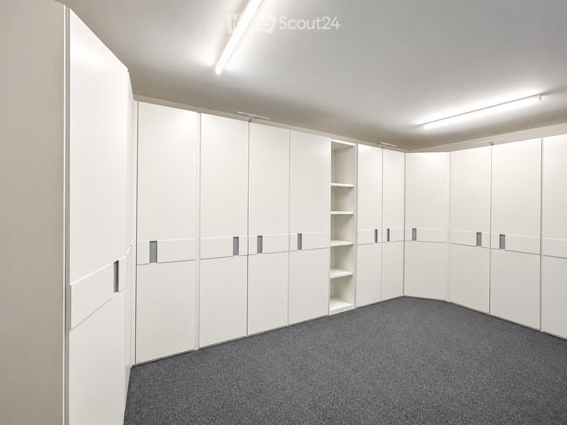 Completely empty room with white built-in wardrobes and grey carpeted floor. No furniture or equipment.
