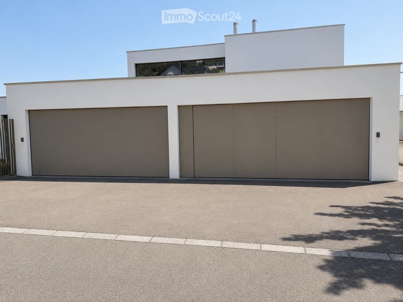 Modern two-story building with white exterior, large garage doors, and clean lines.