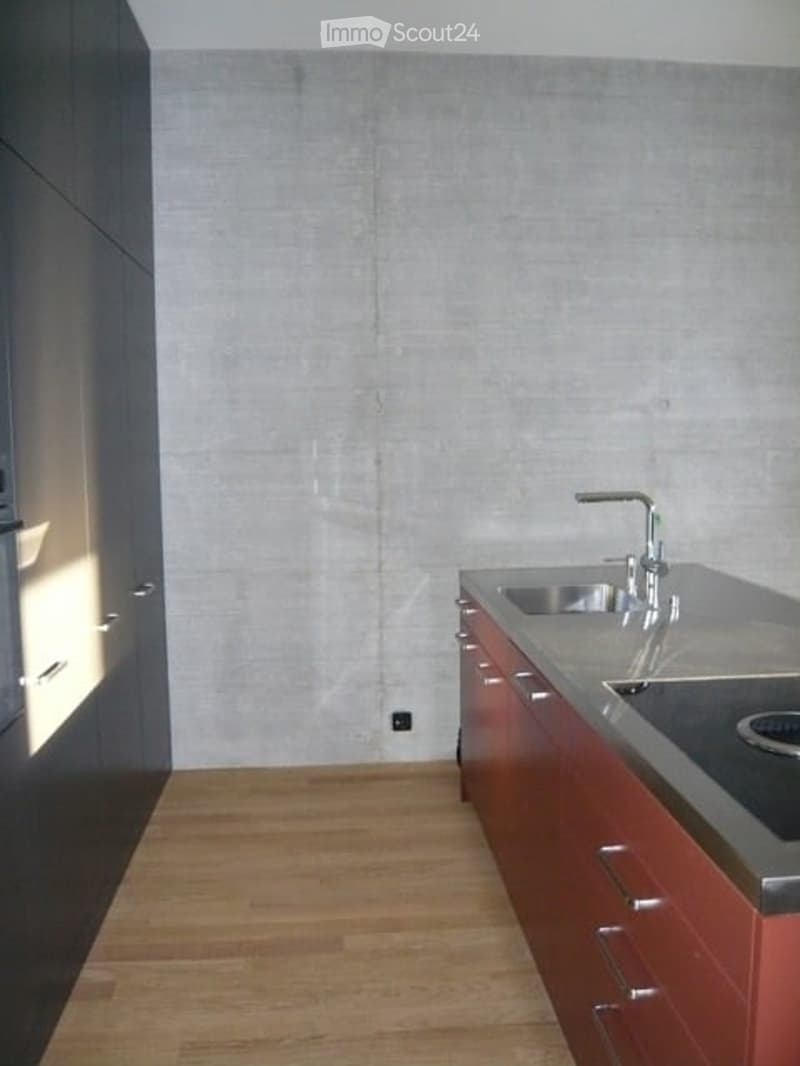 Modern kitchen with wooden flooring, stainless steel sink, and dark cabinets.