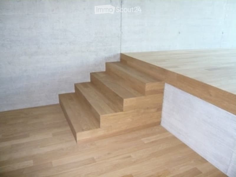 Wooden staircase with white walls and light wooden flooring, leading to an upper level.