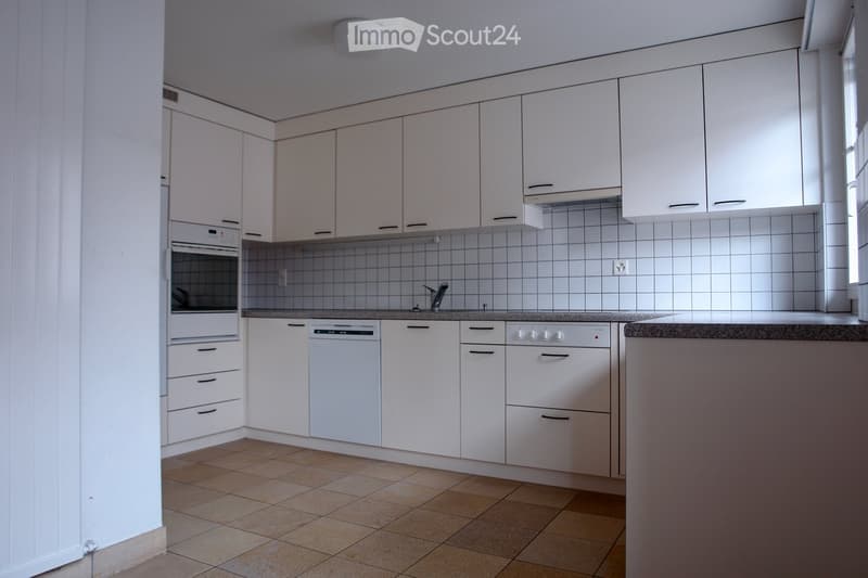 Modern kitchen with white cabinets, tiled backsplash, granite countertop, and built-in appliances including an oven and dishwasher.