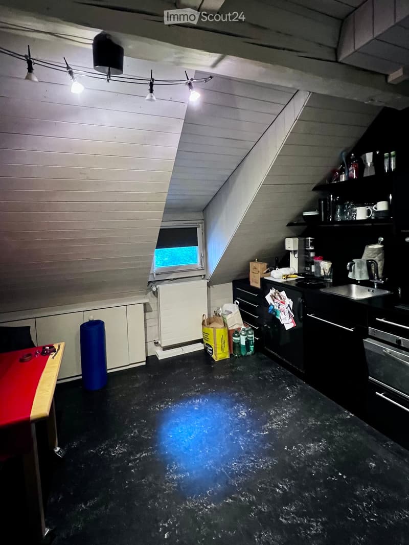 Kitchen with black countertops, white cabinets, and various appliances including a sink, fridge, and oven. There is a small table with a red surface and a blue cylindrical object nearby.