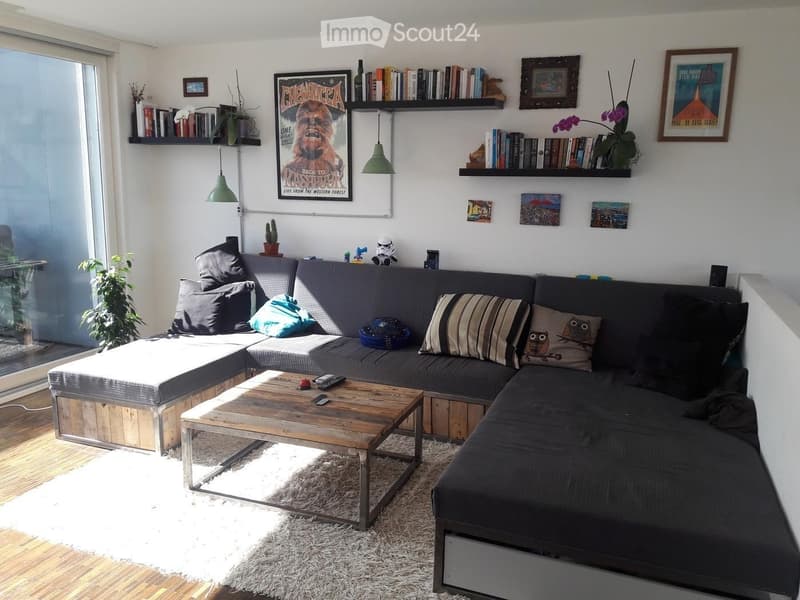 Modern living room with a grey sectional sofa, wooden coffee table, bookshelves, and decorative pillows.