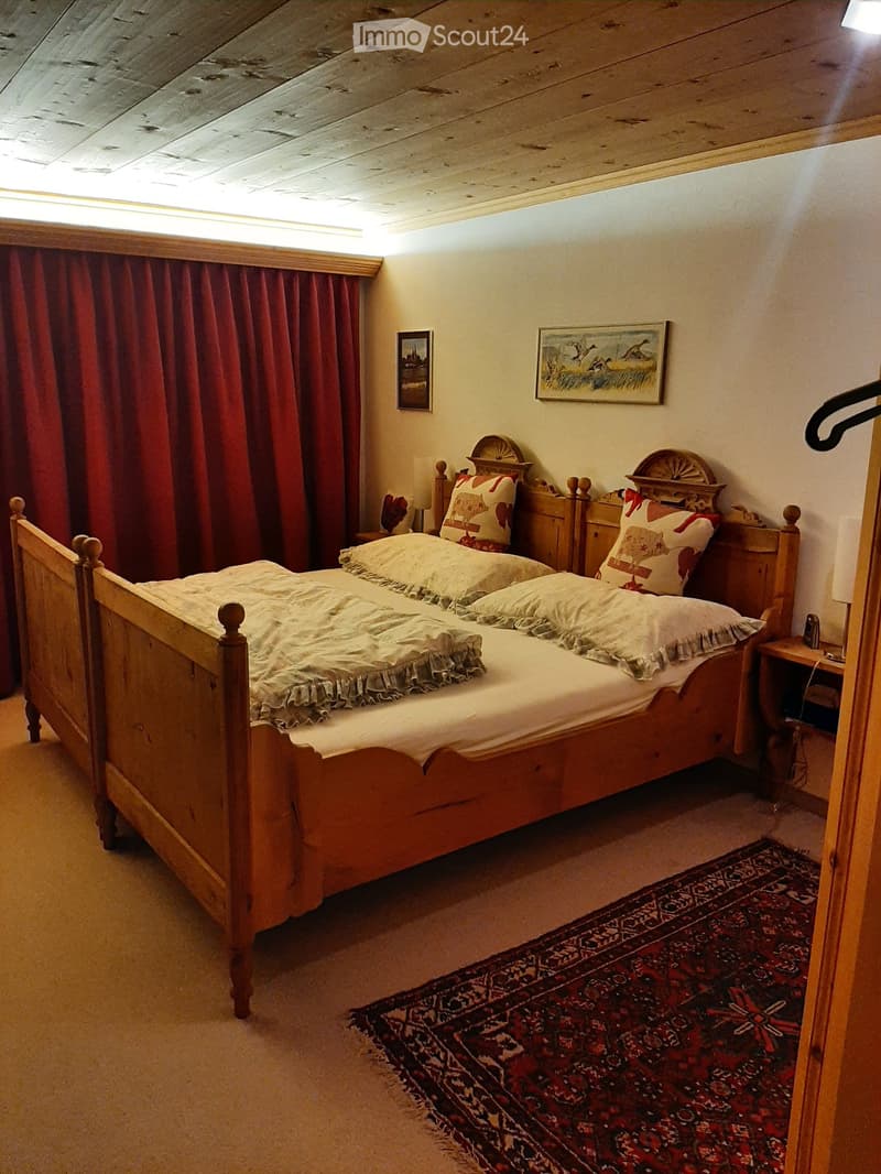 Cozy bedroom with a wooden bed, nightstands, and a patterned rug on the floor.